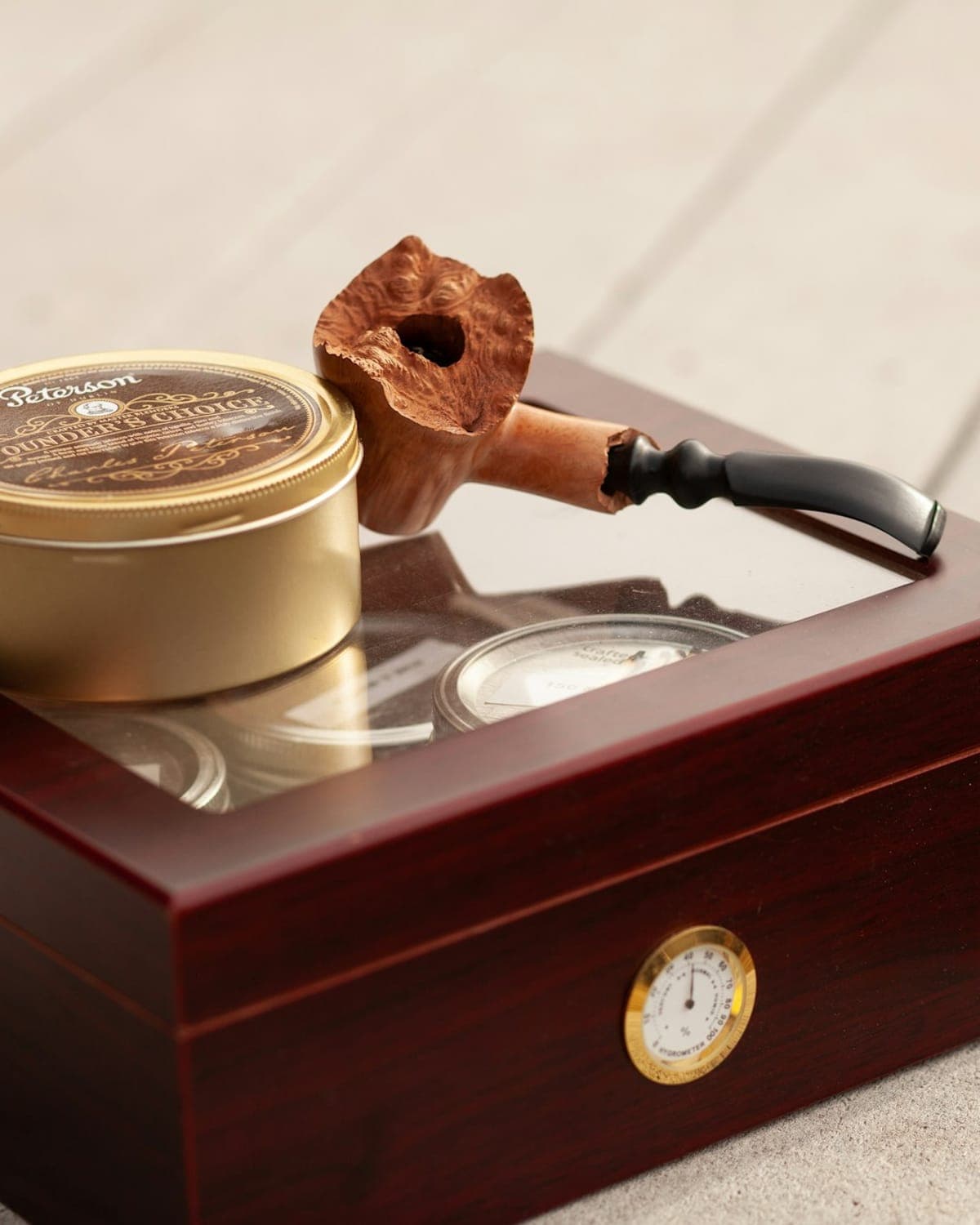 A wooden humidor with a tobacco tin and a pipe resting on top