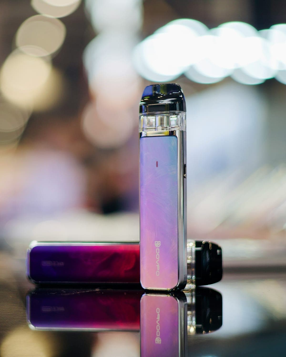 A pink refillable pod device standing on a glass counter