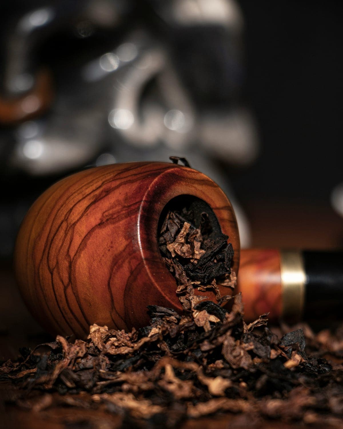 A wooden tobacco pipe bowl filled with loose-cut tobacco